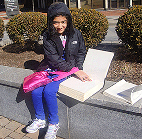 Adhithi Baskar soaks up the sun as she reads her Braille book.