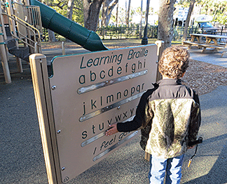 Marcus Lewis investigates the metal Braille strip on the sign in a local Louisiana playground. The sign shows the alphabet and the words �I feel good� in both Braille and large-print letters.