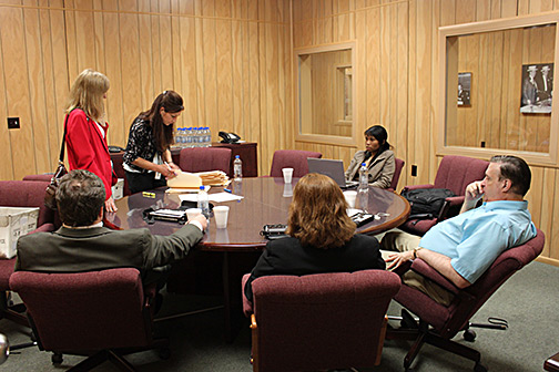 At a smaller round table, a subcommittee of six tackles a thick stack of applications.