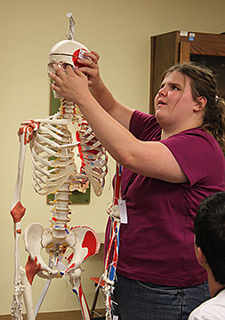 Keby Young reads the Braille label on her skeleton in the human physiology class.
