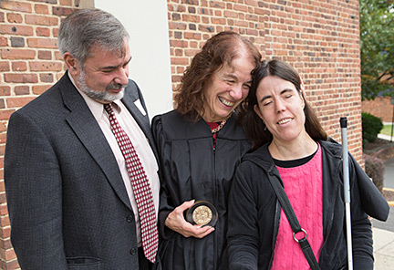 Carol Castellano holds her Douglass Society award as she stands with her husband, Bill Cucco, and their daughter, Serena Cucco.