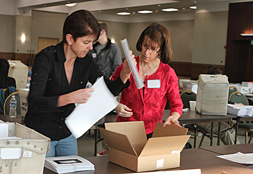 A pair of volunteers box Brailled material for mailing.