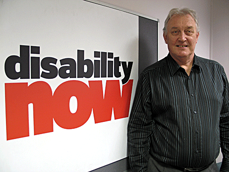 Ian Macrae standing by the lobby sign for Disability Now