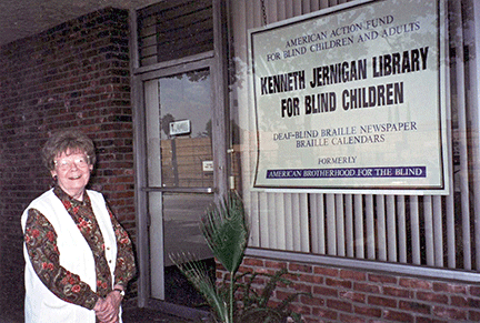 Jean Dyon Norris stands next to the Kenneth Jernigan Library for Blind Children sign in the front window of the American Action Fund office.