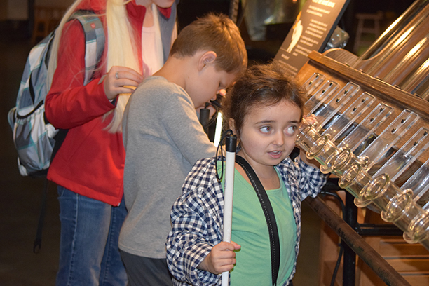 Julia Gebert listens to wind tubes at the Exploratorium.