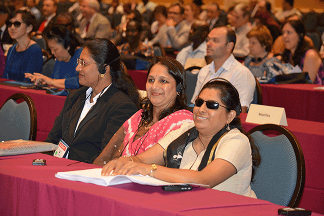 Three of the delegates from India wearing headphones as they listen