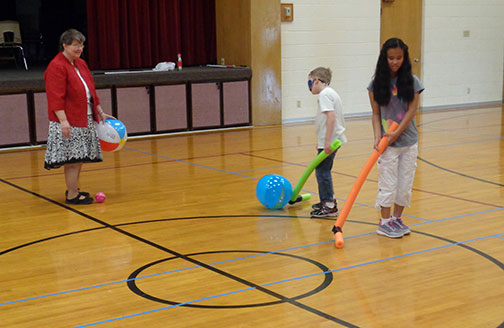 Grant and Lexi play indoor field hockey wearing learning shades.