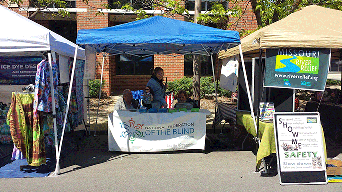 The National Federation of the Blind Columbia Chapter&rsquo;s booth, situated between an organization dedicated to cleaning trash from the Missouri River and a woman selling tie-dye clothing.
