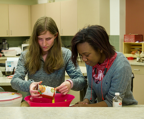 Teammates Rebecca Jackson (left) and Ravi Hudson (right) empty a can into a bowl as they prepare their team's sweet potato waffles