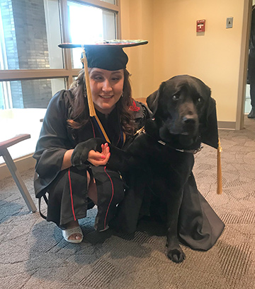 Yevgeniya in her cap and gown posing with her dog.