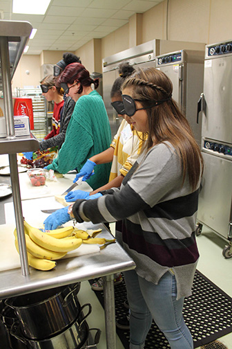Five Art of Leadership students from Baltimore cut fruit while wearing sleepshades.
