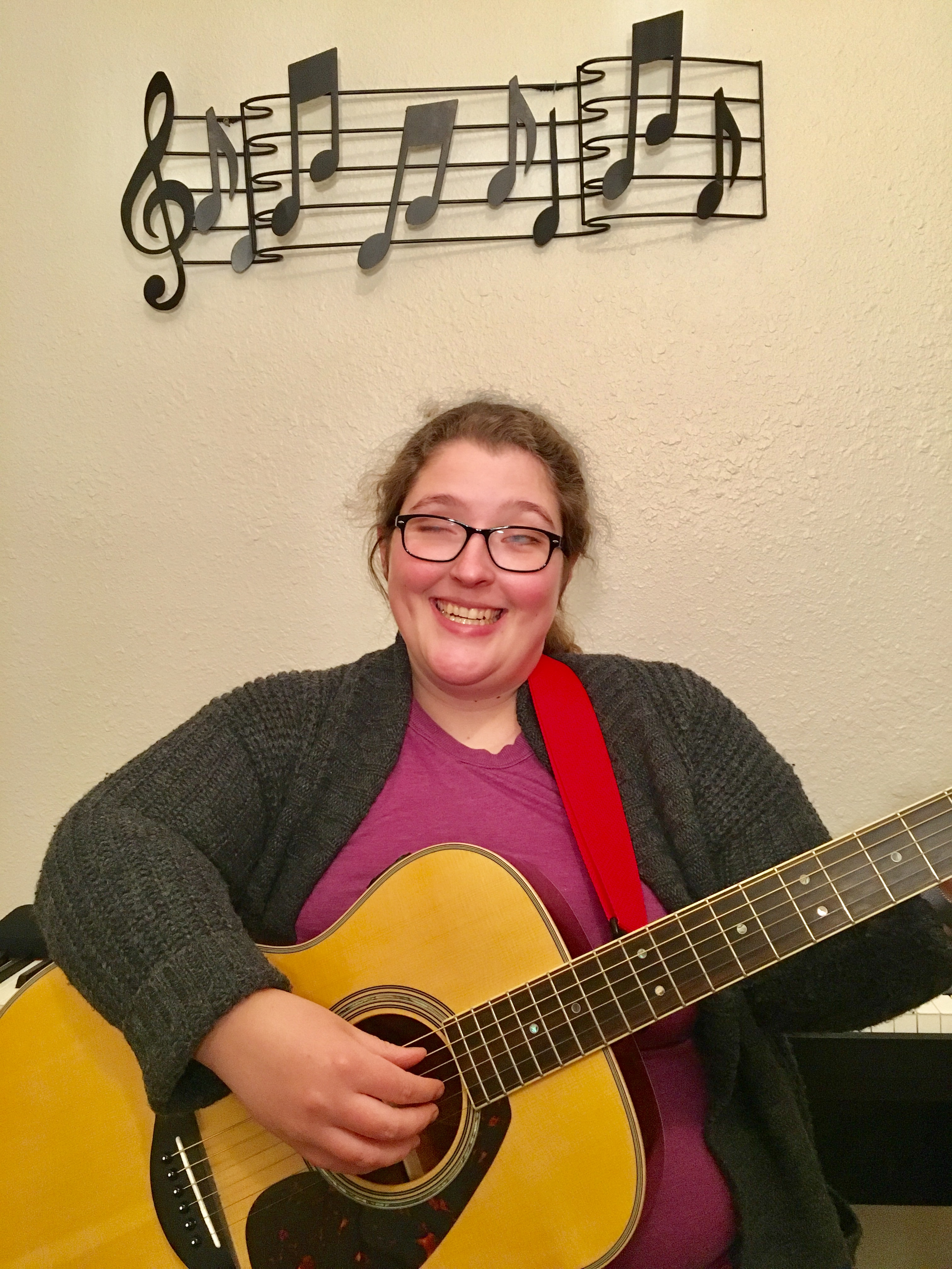 Kaiti Shelton smiles as she plays her guitar.]