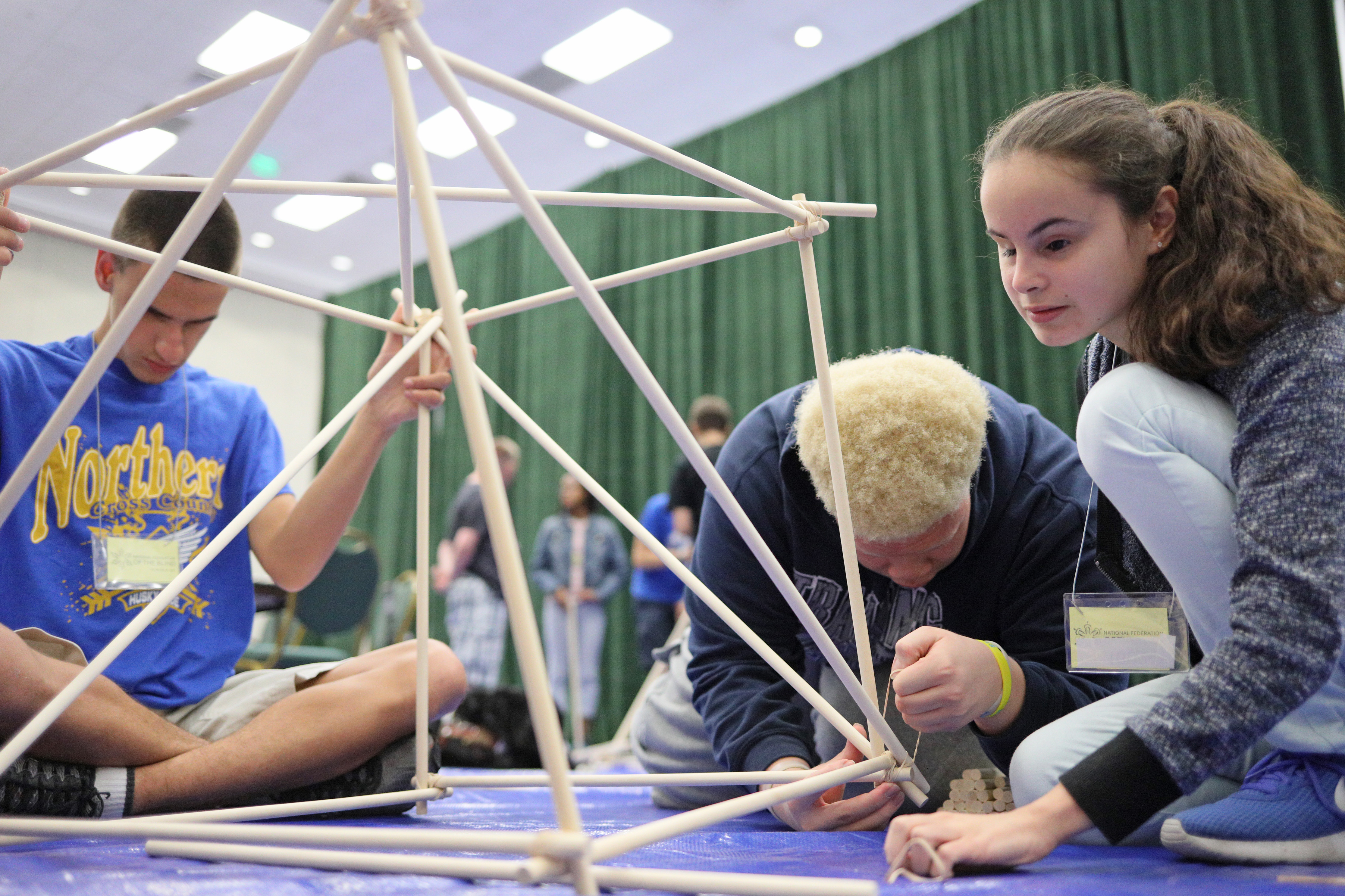 Brandon, Jaden, and Mili complete their structure made of wooden dowels and rubber bands