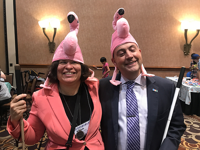 Melissa and Mark Riccobono wearing flamingo hats at the Action Fund Braille Carnival