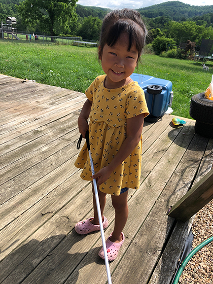 Mae smiles as she stands outside with her new white cane.