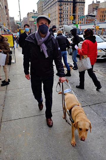 Peter and his guide dog Inga out for a walk on a city street.