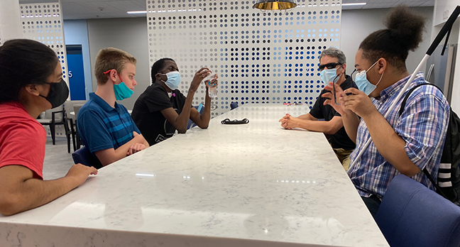 Three blind students talk to two mentors in a small group session.
