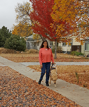 Jo Elizabeth Pinto walks down the sidewalk with her guide dog.