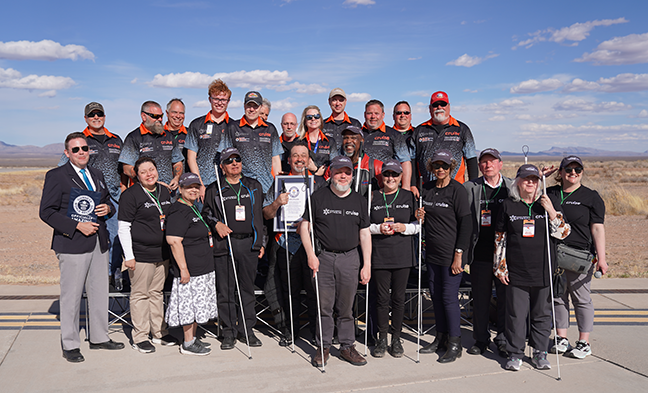 Group shot of Dan Parker—holding his GWR certificate—his crew, and the NFB leadership and staff at the Guinness World Record attempt. The Guinness World Records official smiles along with the group.