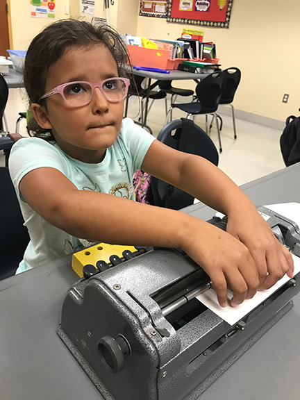 A BELL participant concentrates on checking the Braille she just created using a Braillewriter.