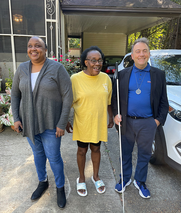 LaShawna Fant and Mark Riccobono smile with Jackson Chapter member Boula outside her home.