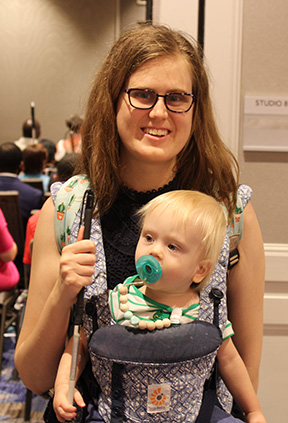 Katelyn MacIntyre smiles while wearing her son in a carrier.