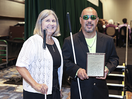 Robin House stands with Tom&aacute;s Cintr&oacute;n who holds his award plaque.