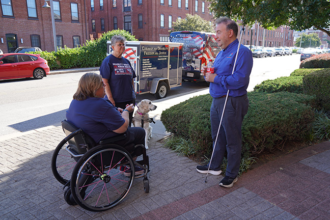 President Riccobono, Sandy and Janet stand talking to each other outside of the Jernigan Institute. In the background is the Caravan.