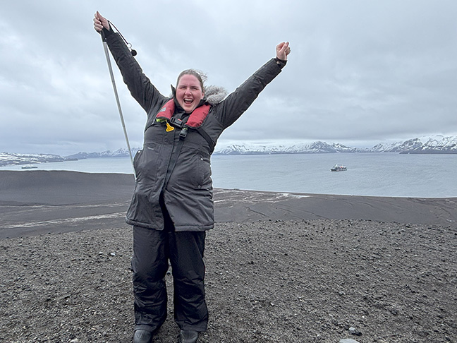 Erin Daley throws her arms up in celebration on Deception Island.