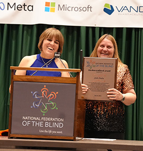 Pam Allen and Julie Deden smile together. Julie holds up her Jacobus tenBroek Award.