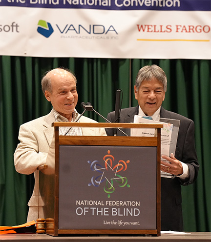Curtis Chong stands holding the Kenneth Jernigan Award while Glen Gordon addresses the banquet.