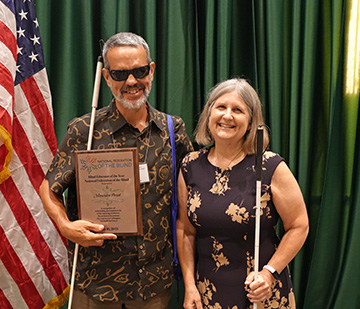 Maurice Peret smiles with Robin House for a photo. He holds his Blind Educator of the Year Award.
