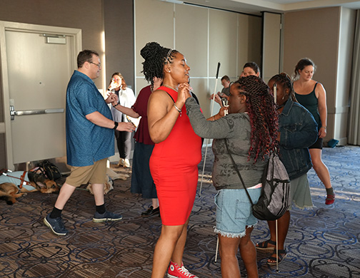 Ahsiyah Abdullah and Alicia Crosson swing dance among a crowd of members dancing.