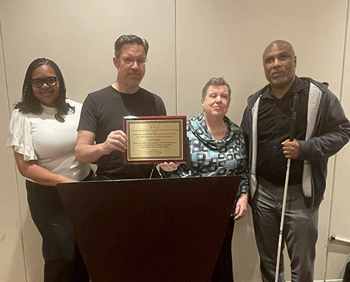 Left to right: Dr. Latonya Callaway, Gail&rsquo;s son David Snider holding up the award, Gail Snider, and Shawn Callaway.