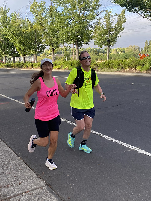 Roger smiles as he runs with his guide, Julia.