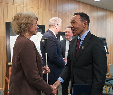 Representative Kweisi Mfume and Ever Lee Hairston shake hands and chat together. President Riccobono can be seen speaking with Senator Chris Van Hollen behind them.