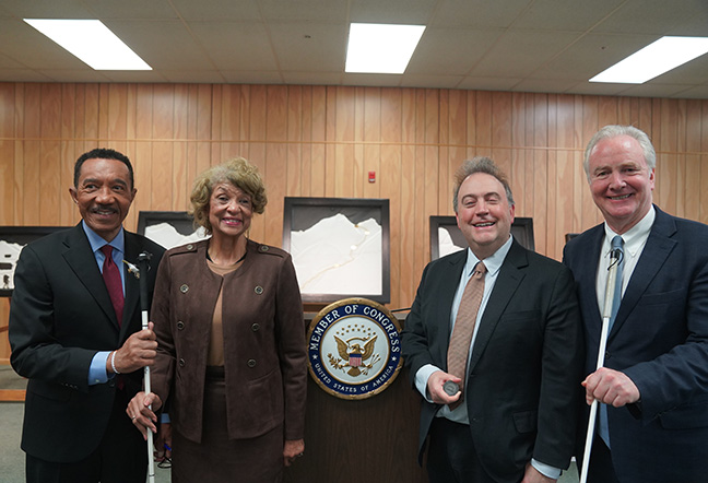 Representative Kweisi Mfume, Federationist Ever Lee Hairston, President Riccobono, and Senator Chris Van Hollen stand together smiling in front of a podium bearing the official seal of a Member of Congress of the United States.