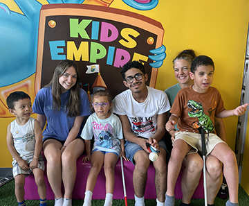 A group of Rhode Island BELL participants and mentors smile together on a field trip to the Kids Empire.