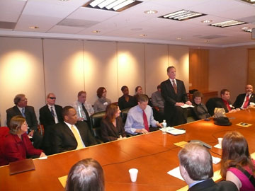 At the table, pictured left to right are Lynnae Ruttledge, commissioner of the Rehabilitation Services Administration; Kareem Dale, special assistant to the president for disability policy; Dr. Alexa Posny, assistant secretary for the Office of Special Education and Rehabilitative Services; Arne Duncan, U.S. secretary of education; President Maurer, standing and reading from a Braille document; Mrs. Patricia Maurer, NFB first lady; Chris Danielsen, NFB director of Public Relations; and Kevan Worley, president of the National Association of Blind Merchants.