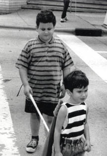 These two children, one blind and one sighted, stay together as they independently follow an adult (not pictured).