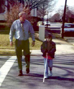 Mr. "Bill" Van Buskirk and Rachel cross a street during a mobility lesson.
