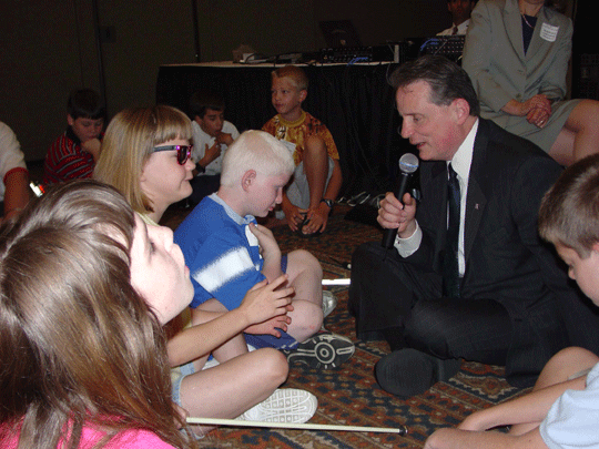 NFB President Maurer sits on the floor for a chat with the children, blind and sighted, prior to the convening of the 2003 NOPBC Parents Seminar.   You can be sure he will be asked to do a repeat performance at the 2004 NFB Convention which will take place at the Marriott Marquis Hotel in Atlanta, Georgia, from June 29 - July 5.   The NOPBC events will begin on Tuesday, June 29.  It will be a week