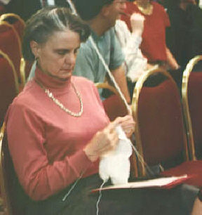 Barbara Pierce's "educated fingers" make the knitting needles fly as she listens attentively in a meeting.
