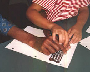 This blind mentor uses a hand-over-hand approach as he demonstrates the use of a slate and stylus.