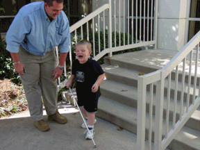 Lance squeals with delight as he practices using his new cane while his proud dad, Damen Roberts, coaches him.
