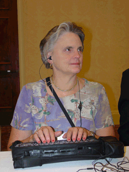 Champion for access technology, Barbara Pierce, diligently records information with her electronic notetaker.