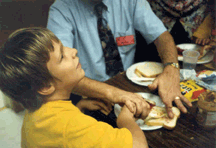 Hands together, this blind tutor and child explore an object together.