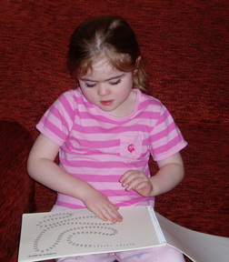 Harmony reading a pre-Braille activity book.