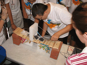 The Youth Slam Engineering track studied not only the mathematics and physics behind the sustainability of bridges, but also the restrictions of a budget for supplies. Here the bridges are put to the test to see how much weight they can withstand.