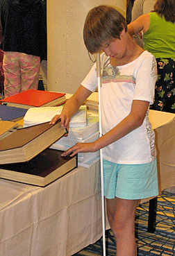Caroline Blair, showing that it�s not difficult to manage a straight cane and browse Braille books. 
